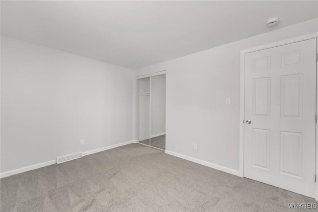 unfurnished bedroom featuring light carpet and a closet