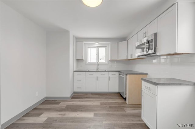 kitchen with light hardwood / wood-style floors, sink, white cabinetry, and stainless steel appliances