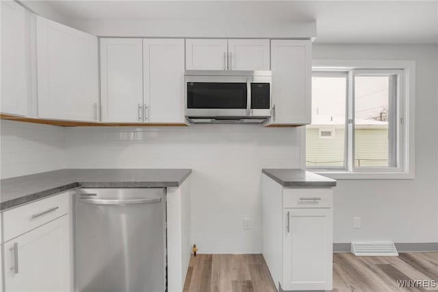 kitchen with light wood-type flooring, white cabinetry, stainless steel appliances, and tasteful backsplash