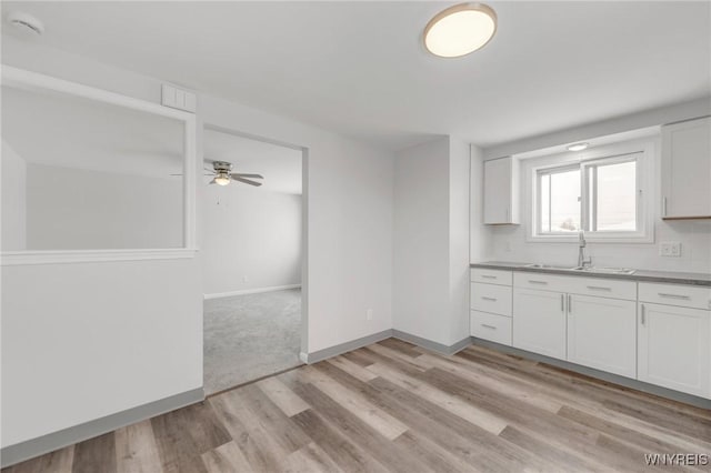 kitchen featuring white cabinets, ceiling fan, light wood-type flooring, and sink