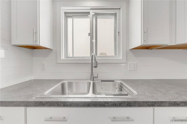 kitchen with decorative backsplash, white cabinetry, and sink