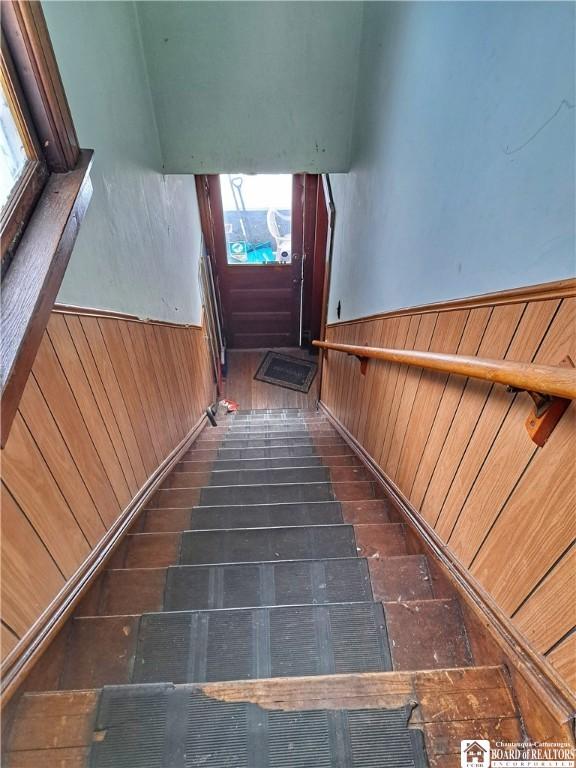 stairs with wood walls, hardwood / wood-style floors, and a healthy amount of sunlight