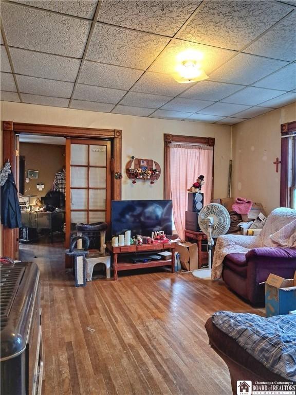 living room with a drop ceiling and dark wood-type flooring