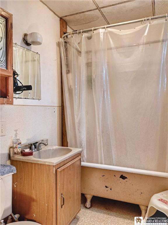 full bathroom with vanity, toilet, a drop ceiling, and shower / tub combo with curtain