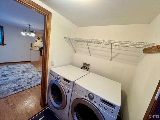 laundry room featuring an inviting chandelier, wood-type flooring, and separate washer and dryer