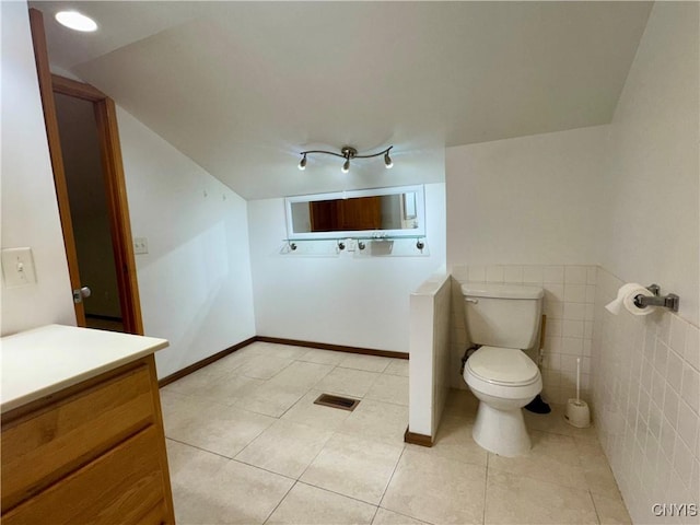 bathroom with tile patterned floors, vanity, tile walls, and toilet