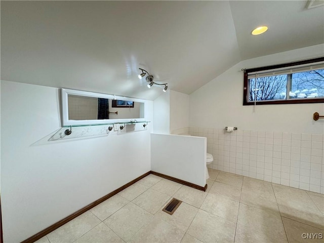 bathroom with tile patterned floors, lofted ceiling, and toilet