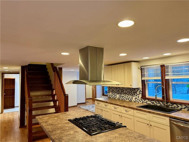 kitchen with dishwasher, sink, gas stovetop, light hardwood / wood-style floors, and island exhaust hood