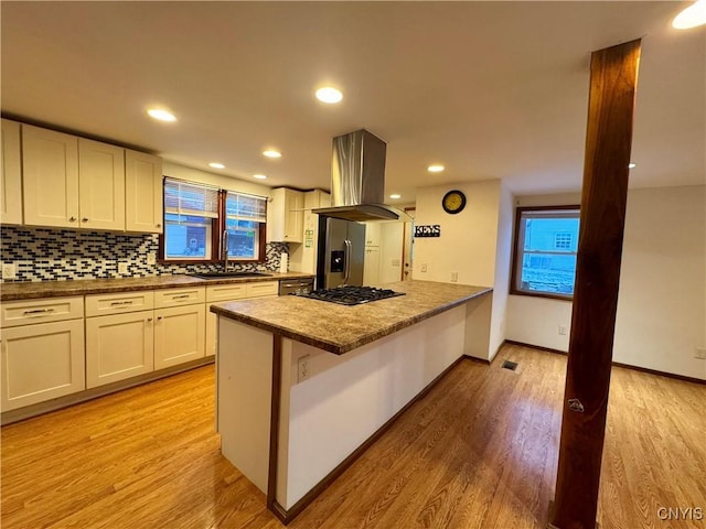 kitchen with island exhaust hood, decorative backsplash, stainless steel appliances, light hardwood / wood-style flooring, and white cabinets