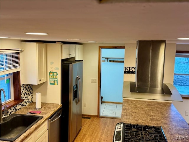 kitchen with sink, stainless steel appliances, tasteful backsplash, light hardwood / wood-style floors, and white cabinets