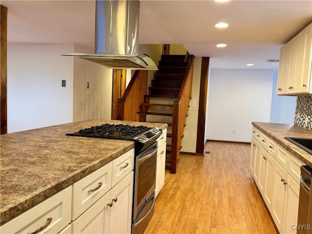 kitchen featuring sink, backsplash, light hardwood / wood-style floors, island range hood, and appliances with stainless steel finishes