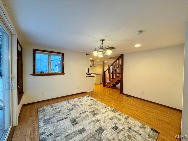 unfurnished room with a chandelier and light hardwood / wood-style floors