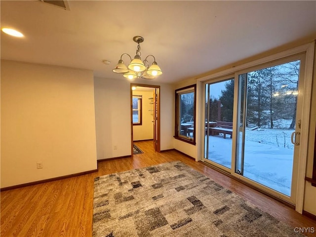 spare room featuring a chandelier and light hardwood / wood-style floors