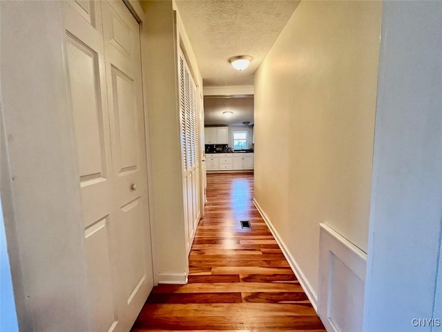 hall featuring a textured ceiling and light wood-type flooring