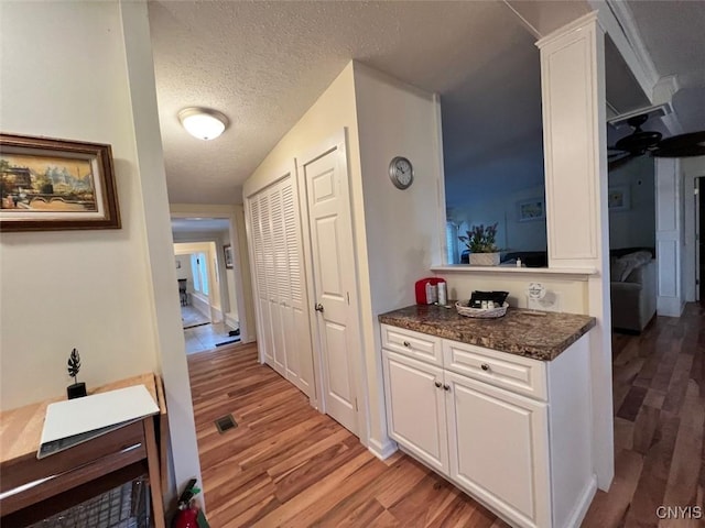 interior space with a textured ceiling, light hardwood / wood-style floors, and lofted ceiling