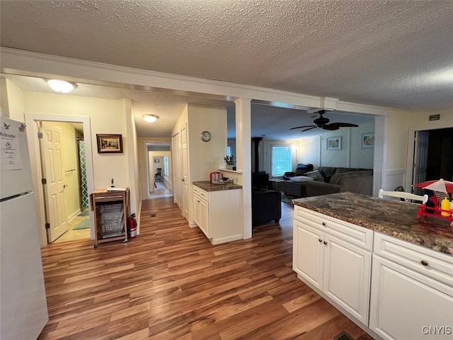 kitchen with ceiling fan, white fridge, a textured ceiling, white cabinets, and light wood-type flooring