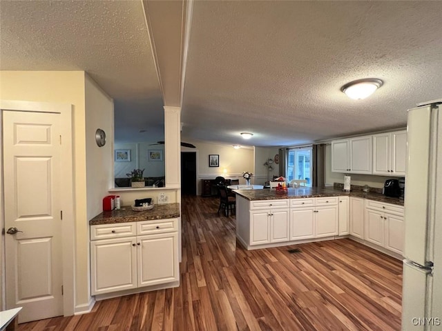 kitchen featuring kitchen peninsula, dark hardwood / wood-style flooring, white refrigerator, and white cabinetry