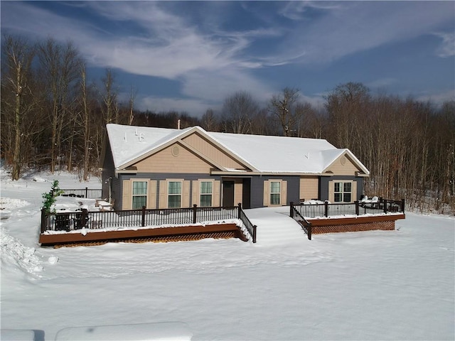 snow covered rear of property featuring a deck