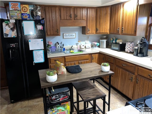 kitchen featuring light tile patterned flooring, sink, and black refrigerator with ice dispenser