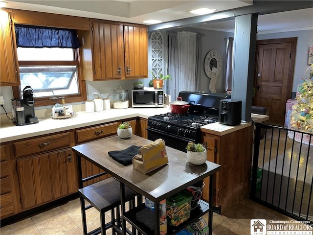 kitchen with black range with gas cooktop, light tile patterned floors, and ornamental molding