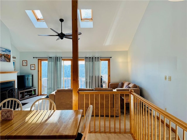 dining area featuring ceiling fan, light colored carpet, and lofted ceiling with skylight