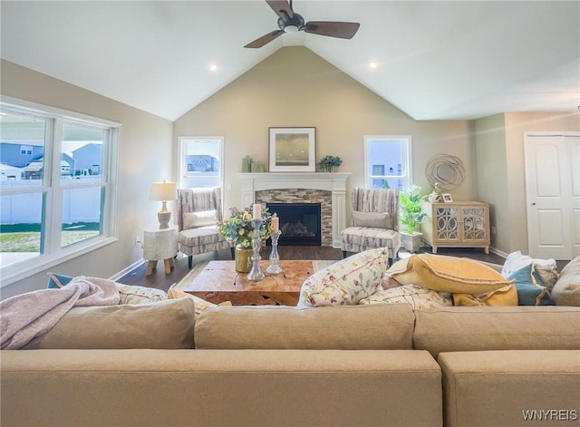 living room with a stone fireplace, ceiling fan, high vaulted ceiling, and hardwood / wood-style flooring