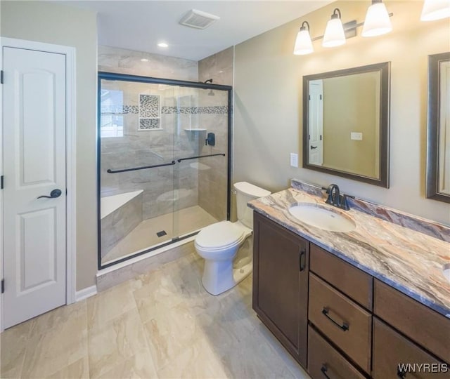 bathroom with vanity, toilet, and a shower with shower door