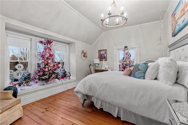 bedroom with hardwood / wood-style flooring, a chandelier, lofted ceiling, and multiple windows