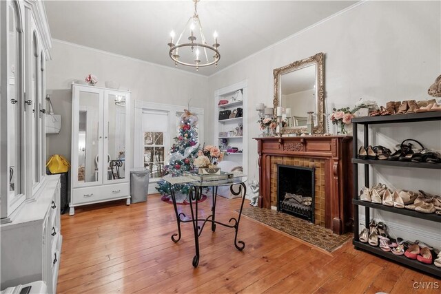 interior space with built in features, an inviting chandelier, light hardwood / wood-style flooring, and ornamental molding