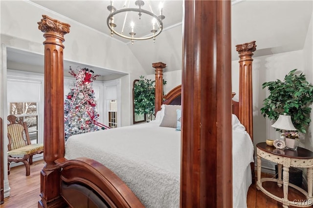 bedroom with crown molding, light hardwood / wood-style floors, lofted ceiling, and an inviting chandelier