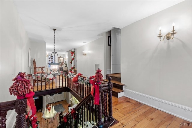 corridor with hardwood / wood-style flooring and a notable chandelier