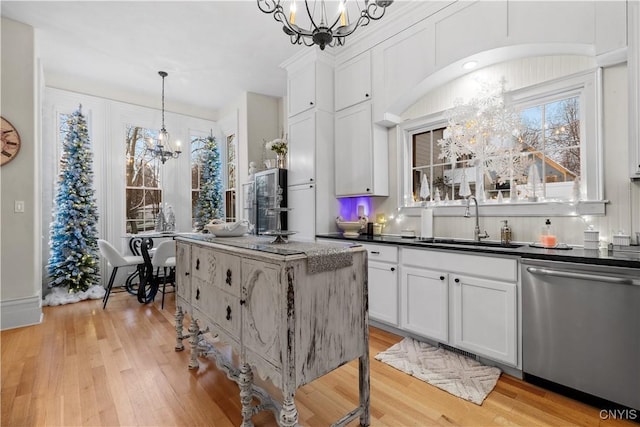 kitchen with light hardwood / wood-style flooring, white cabinets, stainless steel dishwasher, and decorative light fixtures