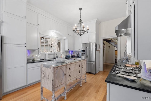 kitchen with stainless steel appliances, exhaust hood, decorative light fixtures, light hardwood / wood-style flooring, and white cabinets