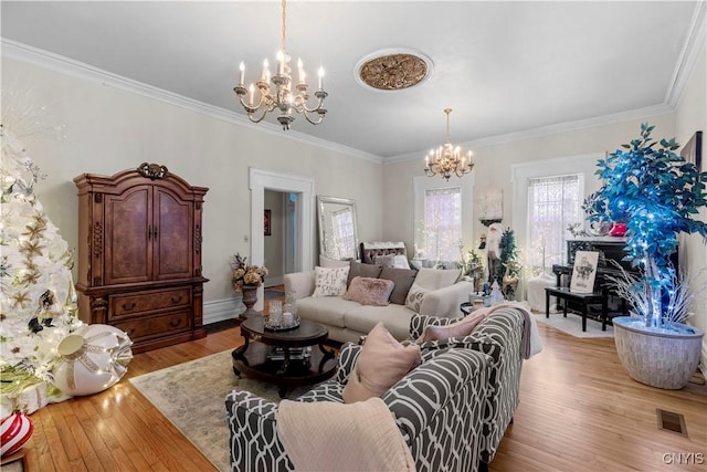 living room with light wood-type flooring, crown molding, and an inviting chandelier