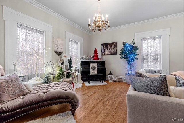 living room featuring hardwood / wood-style flooring, crown molding, a wealth of natural light, and a notable chandelier