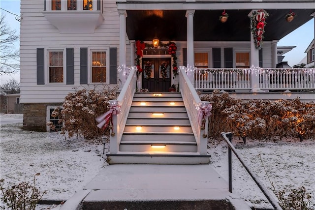 snow covered property entrance featuring a porch