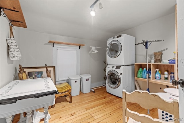 laundry area with hardwood / wood-style flooring and stacked washer / dryer