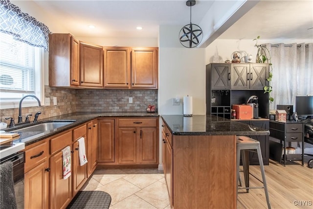 kitchen with a breakfast bar, sink, dishwasher, pendant lighting, and decorative backsplash