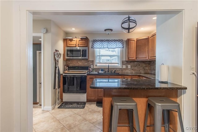 kitchen with white electric range oven, a breakfast bar, sink, kitchen peninsula, and pendant lighting