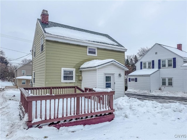 snow covered back of property with a wooden deck