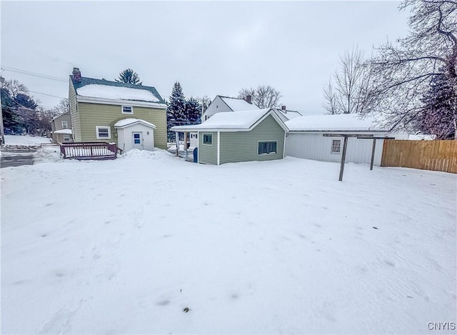 snow covered back of property with a wooden deck