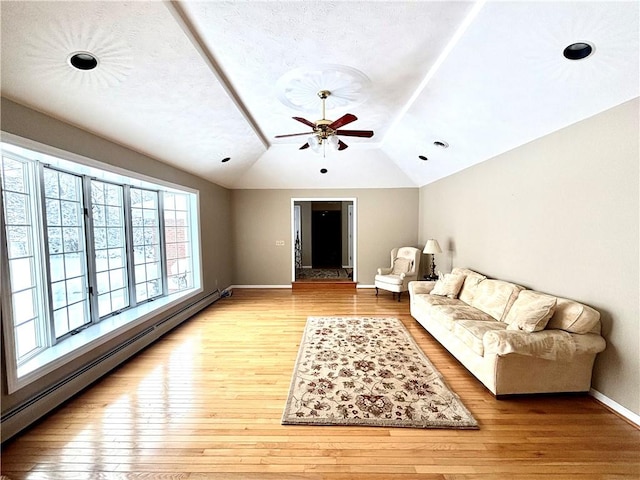 living area with light wood-style floors, baseboards, vaulted ceiling, and baseboard heating