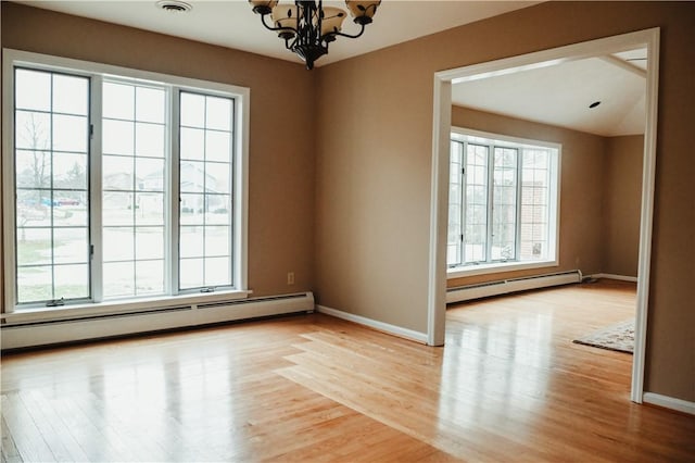 empty room featuring baseboards, baseboard heating, light wood-style flooring, and an inviting chandelier