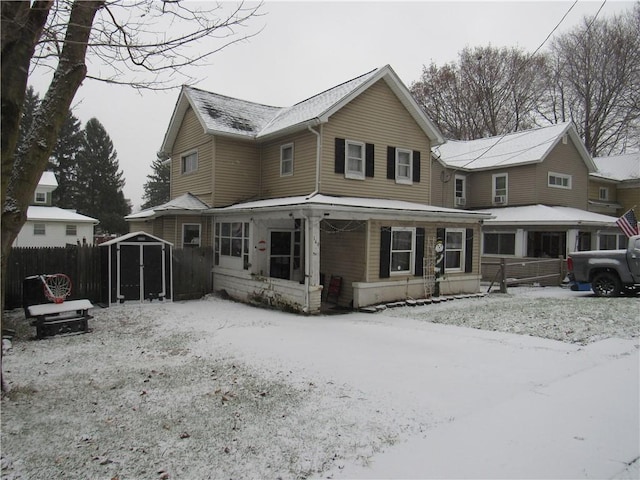 snow covered rear of property with a storage unit