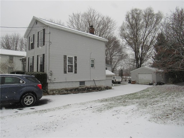 view of snow covered exterior featuring an outbuilding and a garage