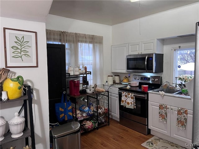 kitchen with white cabinets, appliances with stainless steel finishes, dark wood-type flooring, and sink