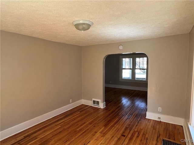 empty room with a textured ceiling and dark hardwood / wood-style floors