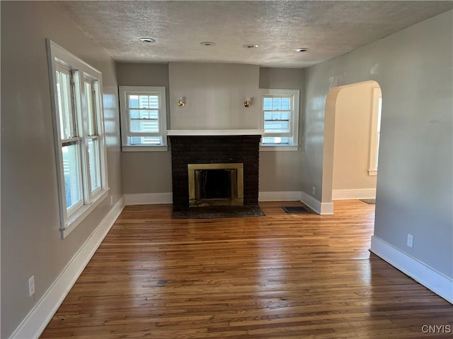 unfurnished living room featuring a fireplace, a textured ceiling, and hardwood / wood-style flooring