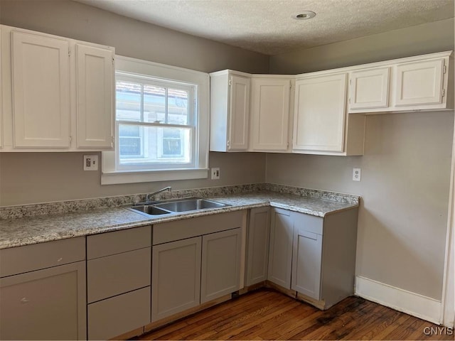 kitchen with white cabinets, a textured ceiling, dark hardwood / wood-style flooring, and sink