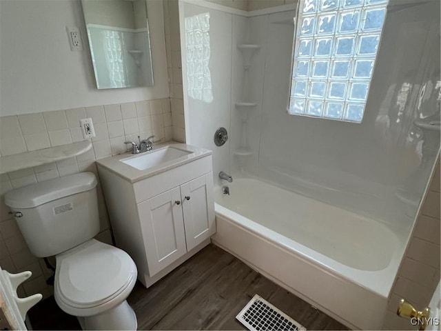 full bathroom with bathing tub / shower combination, hardwood / wood-style floors, toilet, vanity, and tile walls